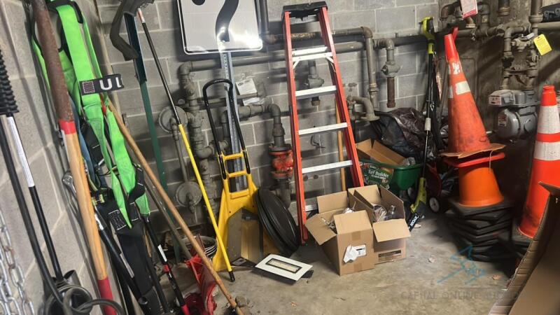 Room full of tools, ladders, rakes, cart, signs, cooler and more